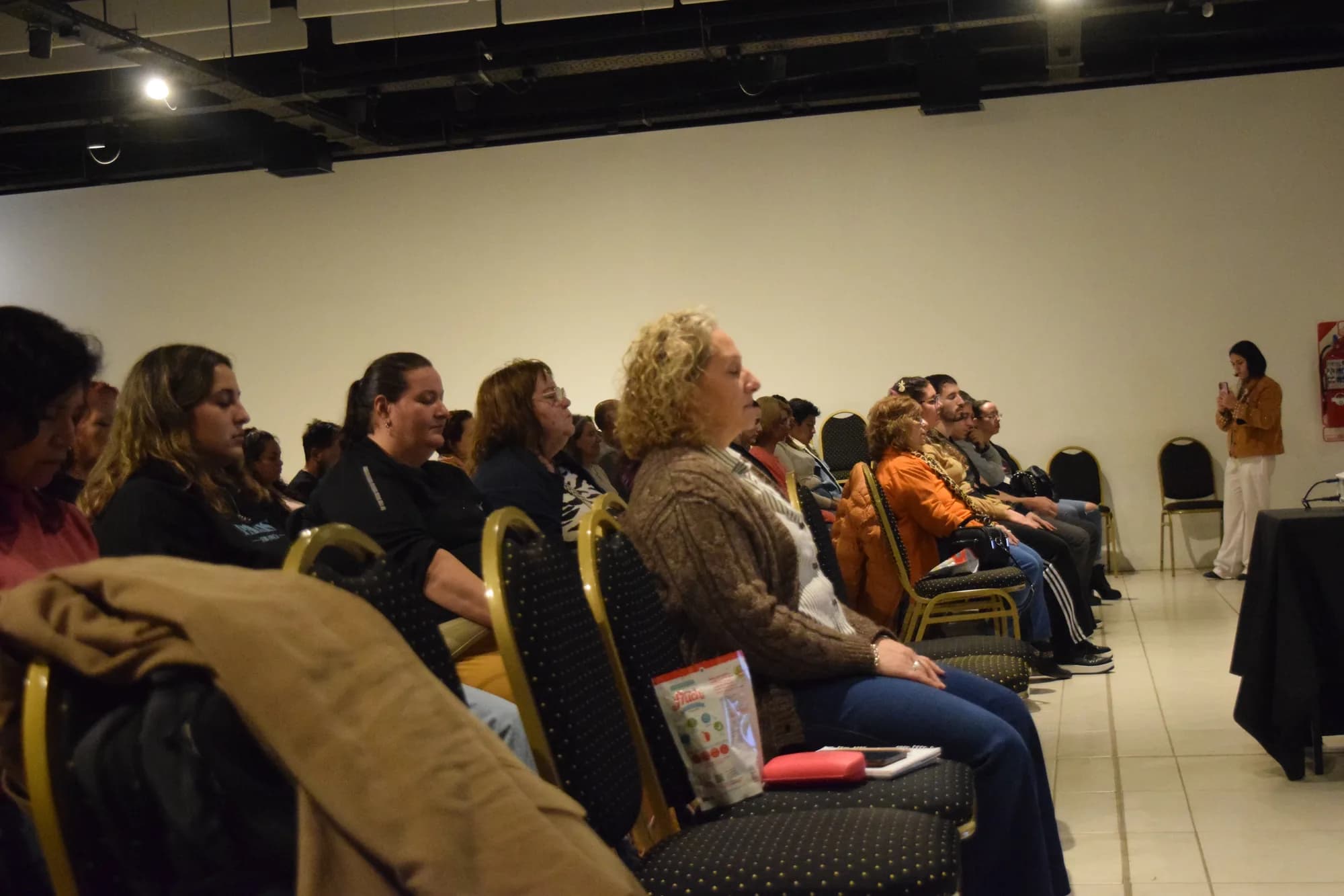 Asistentes sentados de perfil siguen la charla