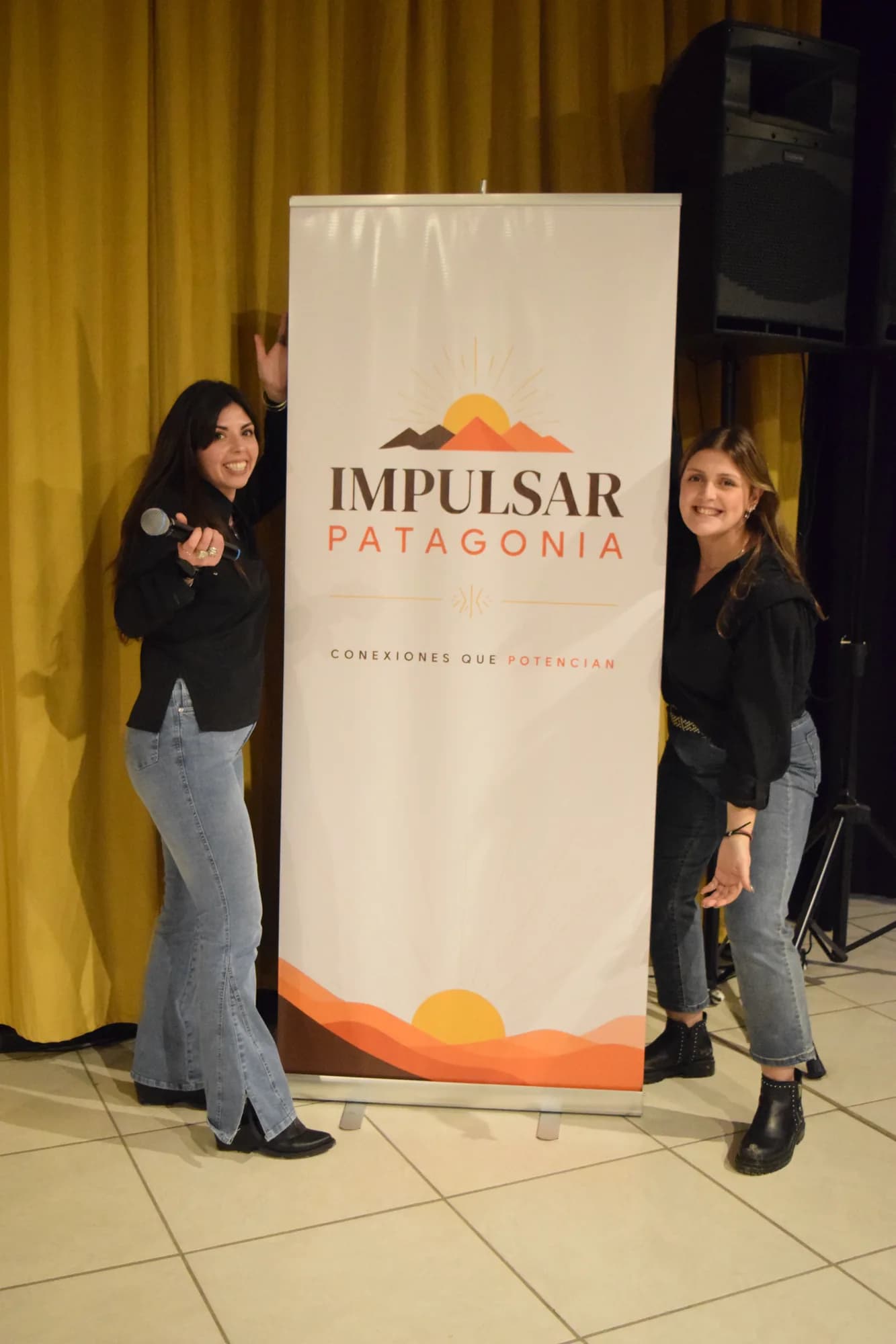 Dos personas posan junto al banner de Impulsar Patagonia