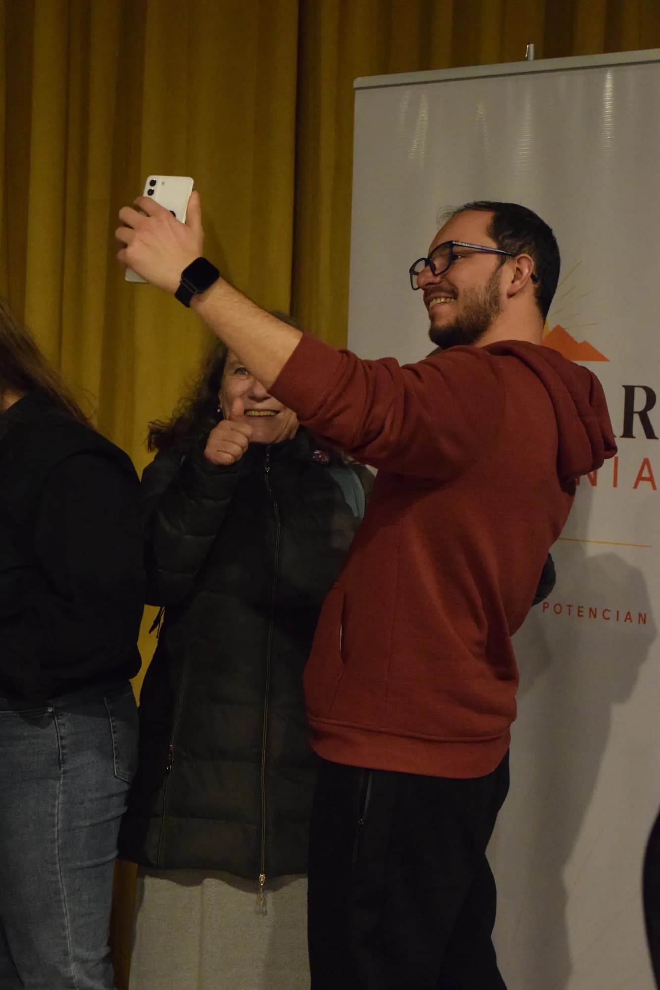 Un asistente se saca una selfie junto al banner